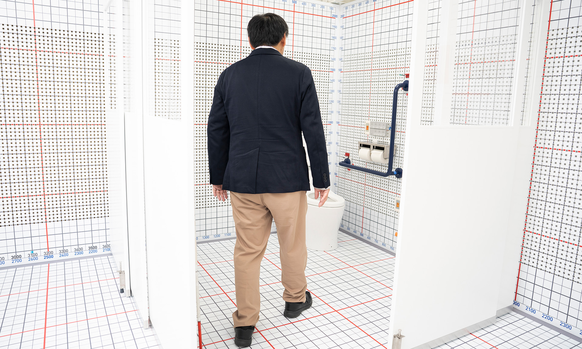 バリアフリートイレの入り口付近から、右斜めの便器付近に向かい大河内さんが歩いている